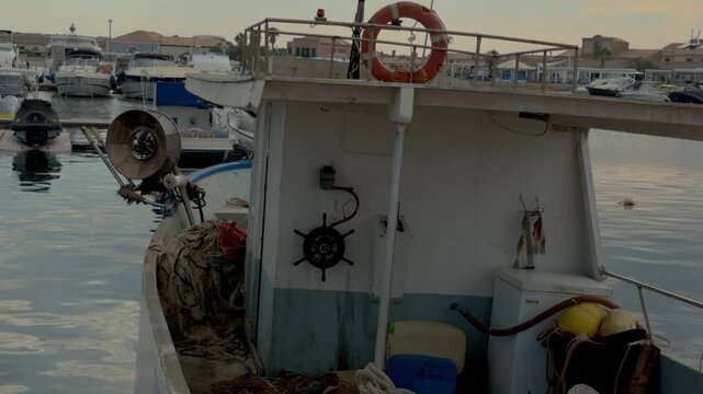 Close shot aboard a traditional fishing boat in Marzamemi featuring ropes, fishing nets and the helm, highlighting Sicilian maritime craftsmanship.