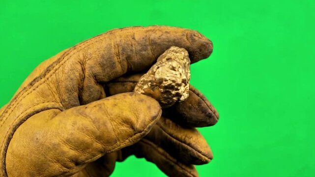 Close-up of a miner&rsquo;s hand holding a chunk of gold, green screen, investment and finance background, 