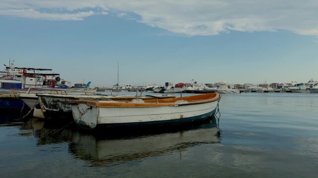 Historic fishing harbor in Marzamemi featuring working boats alongside recreational vessels on the Sicilian Mediterranean coast.
