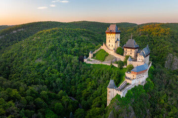 Aerial view of iconic gothic royal Karlstejn Castle surrounded by lush green forests at golden hour sunset, UNESCO candidate site, Central Bohemia, Czech Republic ( Hrad Karlštejn-Česká Republika ) © Miroslav
