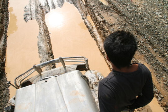 Truck driver looking at flooded muddy road ahead