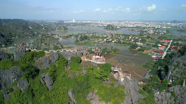 Aerial view of Hang Mua Viewpoint overlooking the limestone karst landscape of Ninh Binh, Vietnam. Scenic panorama with rice fields, mountain peaks and traditional architecture.
