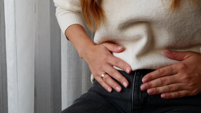 Close-up of woman holding lower abdomen with severe pelvic pain during menstruation