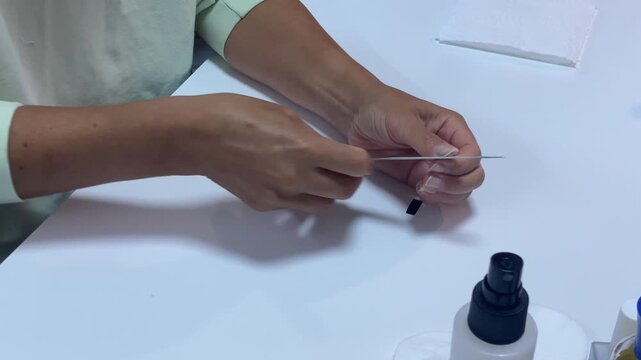 A woman carefully files her nails at a white table. She shapes them with calm focus and gentle care. This simple grooming routine feels peaceful and satisfying.