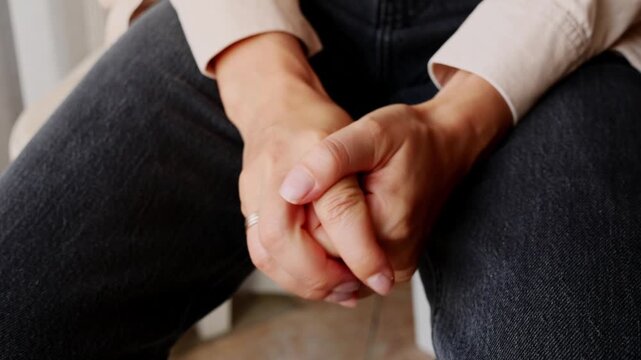 Close-up of nervous woman clasping hands with anxiety, stress and emotional distress