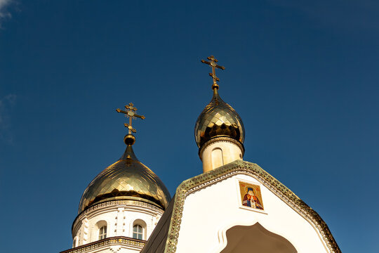 Golden orthodox church domes with crosses against a clear blue sky