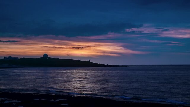 Beautiful sunset sky with orange and purple clouds over the silhouette of Fuguijiao Lighthouse and radar station on the coast of Shimen, Taiwan.