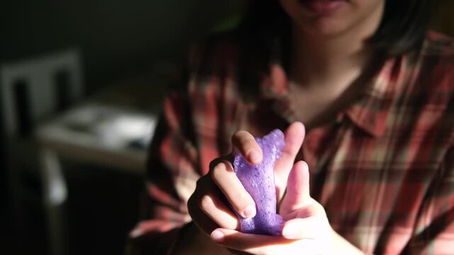 Playing with homemade purple slime, stretching the slime in the hands to the sides, an engaging sensory activity, concept for educational content, toy stores, and child development at home. 
