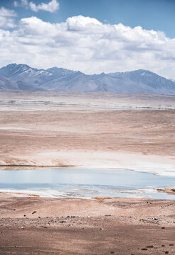 Panorama of a mountain landscape with a lake and river with clear water on a plateau in the Tien Shan Mountains in the Pamirs, mountain ridges and slopes with snow in the background