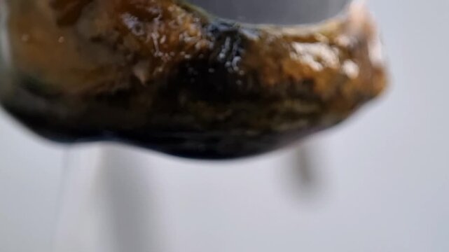 Macro close-up of water dripping from dirty corroded rusty pipe leak