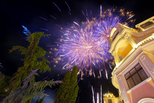Colorful fireworks exploding above an illuminated historic building during a festive night celebration. Spectacular fireworks display lighting up the night sky over elegant architecture with copy spac