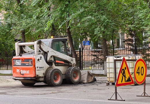 White and orange Bobcat skid steer loader used for roadworks: Abakan, Russia - July 25, 2026