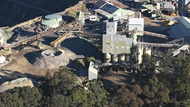 Cinematic drone footage captures Montrose Quarry&rsquo;s rugged machinery and aggregate piles in Melbourne, illuminated by natural daylight. Industrial plant, conveyors, and forest edge visible. No people.
