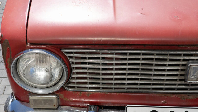 VAZ 2101 classic Soviet automobile front detail showing round headlight, chrome grille, vintage design elements and signs of long term vehicle use