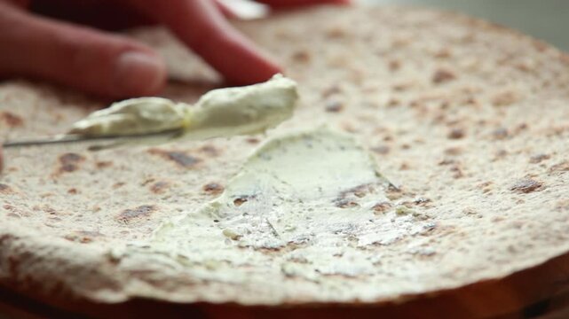 Spreading Fresh Cream Cheese on Baked Wrap Bread Close Up