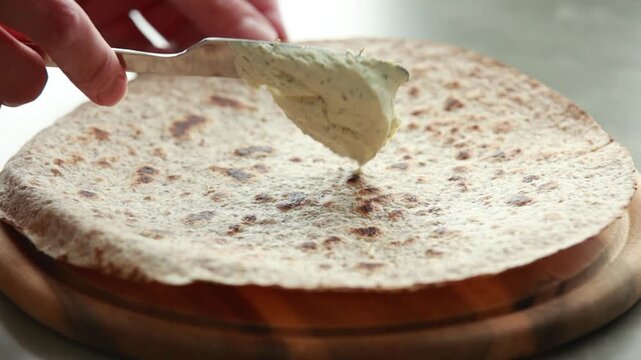 Spreading Fresh Cream Cheese on Baked Wrap Bread Close Up