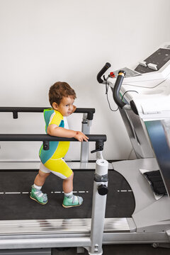 Young boy is using a treadmill for therapy in a rehabilitation center. He is focused on walking