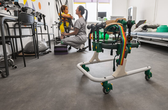 Rehab walkers for young boy with movement disorders who, in the background, is rehabilitating with a physical therapist