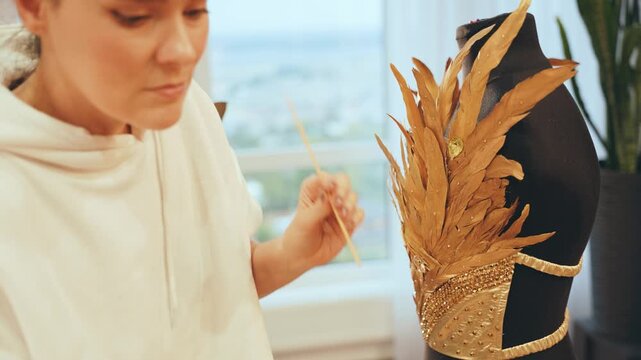 process of work professional tailor hands close-up decorate corset on mannequin, fasion designer glues shiny rhinestones on golden feathers dress. tailoring creative clothes evening gown to order
