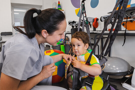 Children's rehabilitation. Physical rehabilitation session for a boy with motor disorders with a female physical therapist