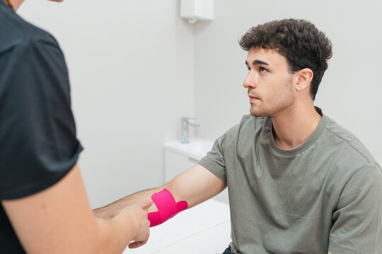 Physical therapist applying kinesiology tape arm patient