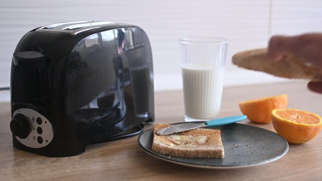 Hand picking up buttered toast from a breakfast plate