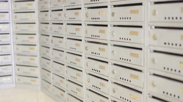 Series of close-up frames showing a row of silver mailboxes with gold nameplates, highlighting the details and arrangement of the mailbox structure in a postal setting