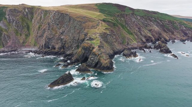 Aerial drone tracking shot around the dramatic coastal promontory and sheer sea cliffs of Fast Castle Head, Berwickshire, Scotland
