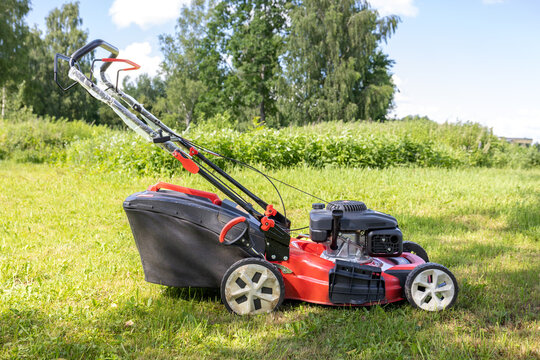 Gasoline lawn mower with grass collection bag on freshly mowed lawn on a sunny summer day