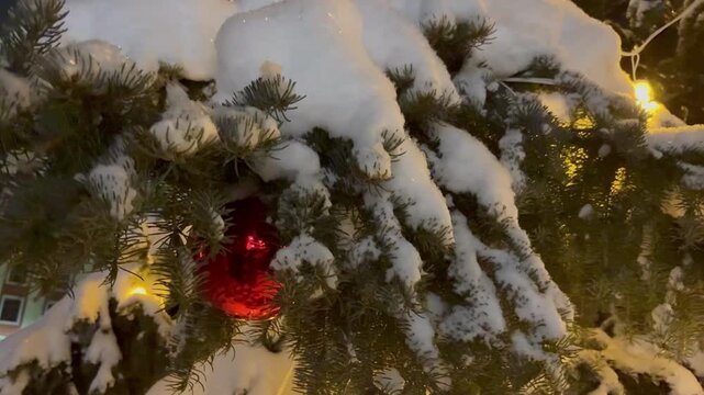 A night scene with a Christmas tree and snowfall in a city square. Winter holiday