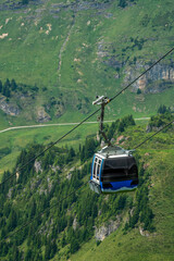 Cable car gondola above green mountain landscape in the Swiss Alps, Switzerland. © Anastazja