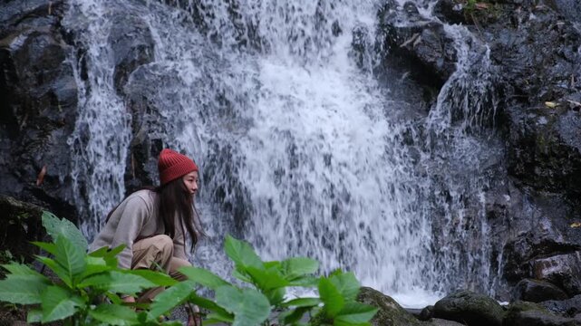 A woman touching and playing with water in the waterfall