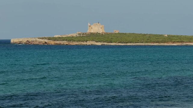 Cinematic close view of Isola di Capo Passero and its historic ruins surrounded by the Mediterranean Sea.