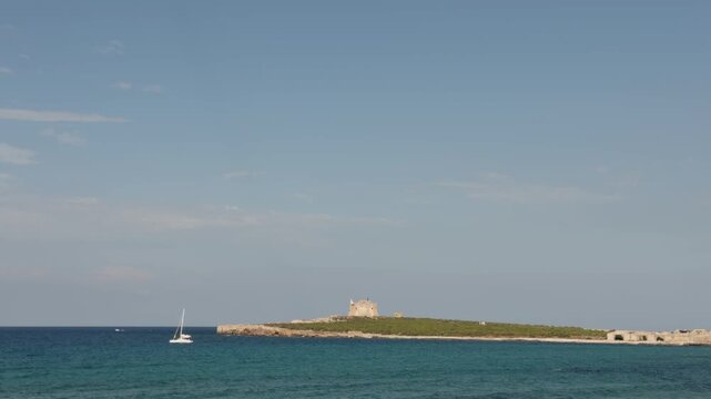 White catamaran sailing across the Mediterranean Sea near Isola di Capo Passero in Sicily.