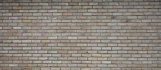 Fototapeta premium Horizontal view of variegated brown brick and mortar wall surface with porous, uneven bricks, smooth faces, chipped and cracked areas, and darker brown mortar joints