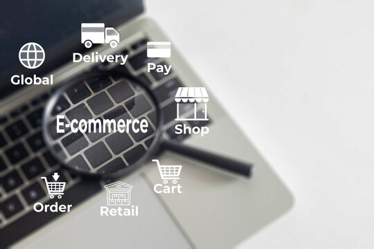 E-commerce and online shopping concept. Magnifying glass on a laptop keyboard focusing on E-commerce text with retail, delivery, and payment icons. Digital marketing and global business.