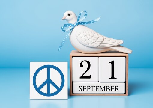 A white dove figurine with a blue ribbon sitting on a wooden calendar block showing september 21st for peace day