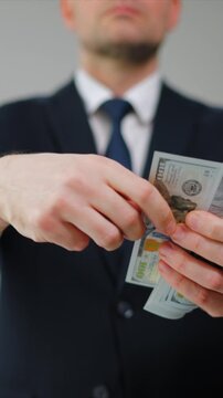 Formally dressed man carelessly throws US Dollar bills towards the camera