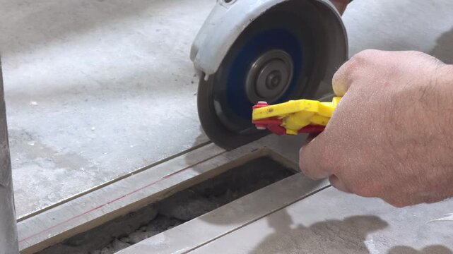 Cutting ceramic tile with an angle grinder and diamond blade along a marked line in close up
