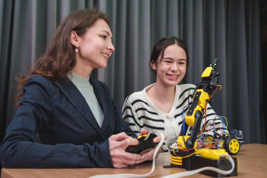 Teacher mentors a student building and programming a robotic arm in a STEM workshop, encouraging engineering, coding, teamwork, and innovation.