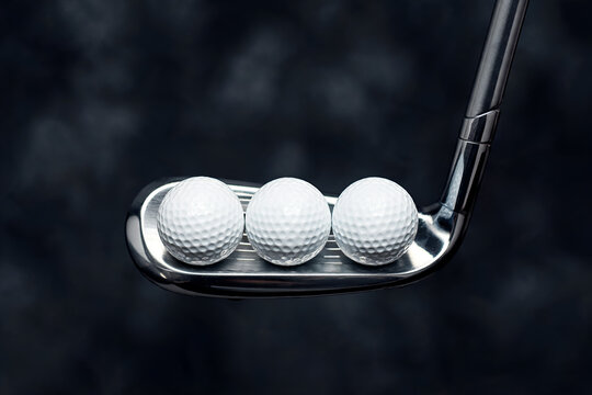 Golf club and balls Sports equipment Close up golf ball Dimpled surface Dark textured background Outdoor game