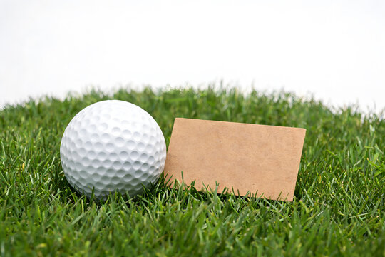 White golf ball and blank tag on green grass Sports equipment for golf game Isolated on white background copy space