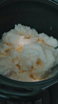 close view of scooped frozen dessert resting in dark round pot, showing moist crystalline texture and soft