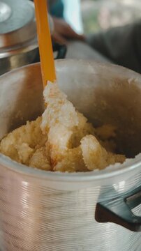 closeup kitchen scene shows orange spatula lifting coarse mixture while clear liquid pours into brushed