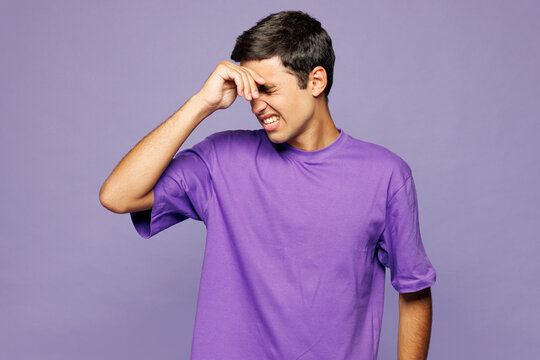 Young sad Caucasian man wear violet t-shirt casual clothes put hand on face facepalm epic fail mistaken omg gesture isolated on plain pastel light purple background studio portrait. Lifestyle concept.