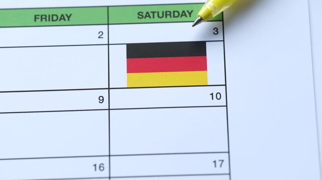 A yellow pen points to the Day of German Unity date of October 3rd marked with a Germany flag on a calendar grid