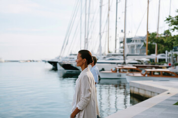 Fototapeta premium A couple walks hand-in-hand along a picturesque marina boardwalk, immersed in each other's company, embracing the beauty of their surroundings and the spirit of togetherness.