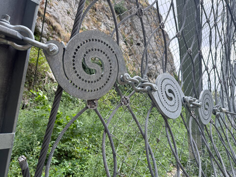 Disc brake elements on a rockfall protection net below a cliff