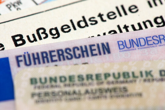 Ein Bu&szlig;geldbescheid liegt zusammen mit einem F&uuml;hrerschein und Personalausweis