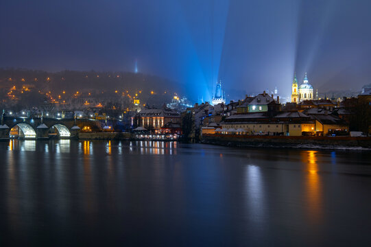 Prague night winter cityscape with Charles Bridge and light beams, Czech Republic